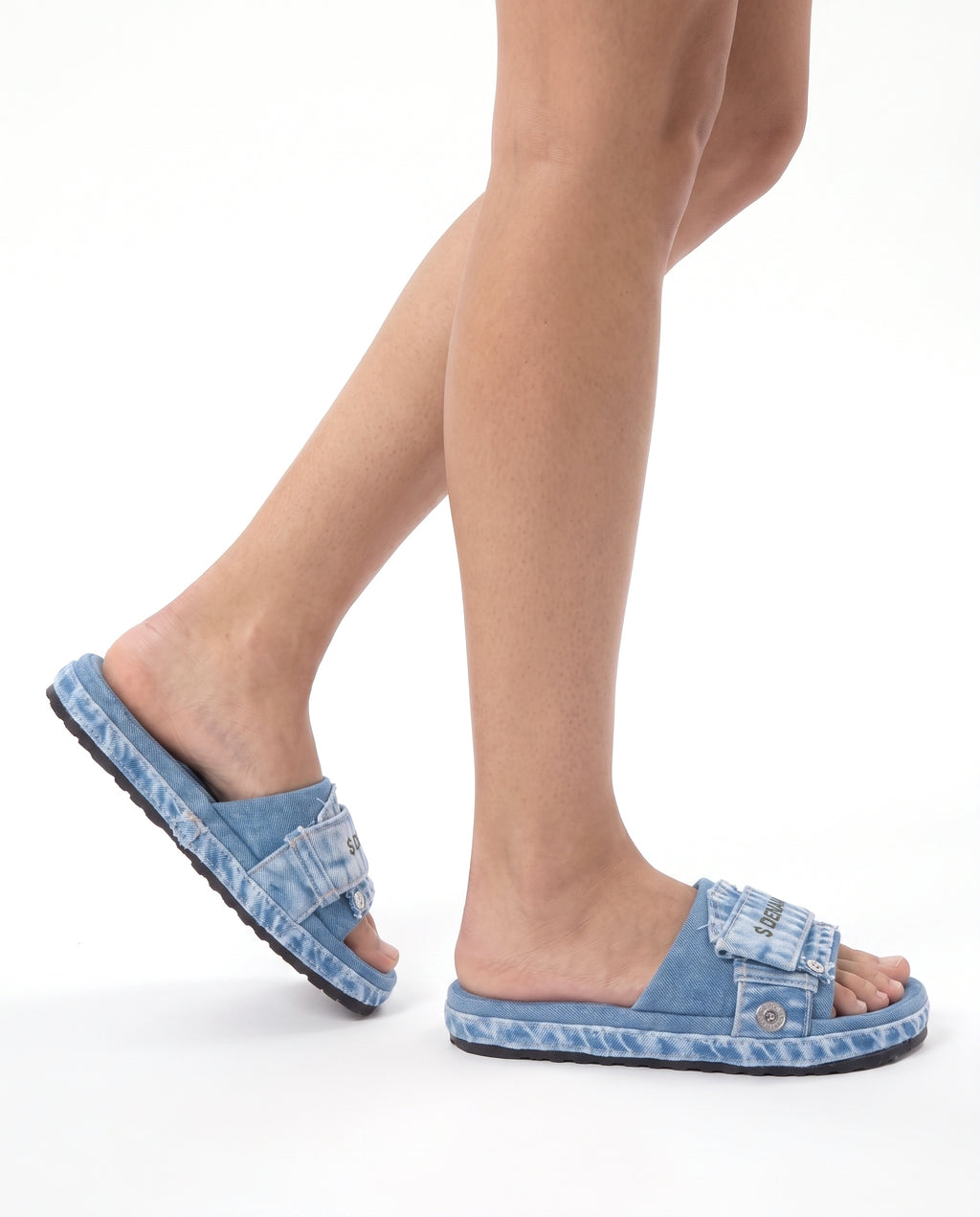 Model wearing the Denaro Denim Slide in light acid-wash denim, mid-step