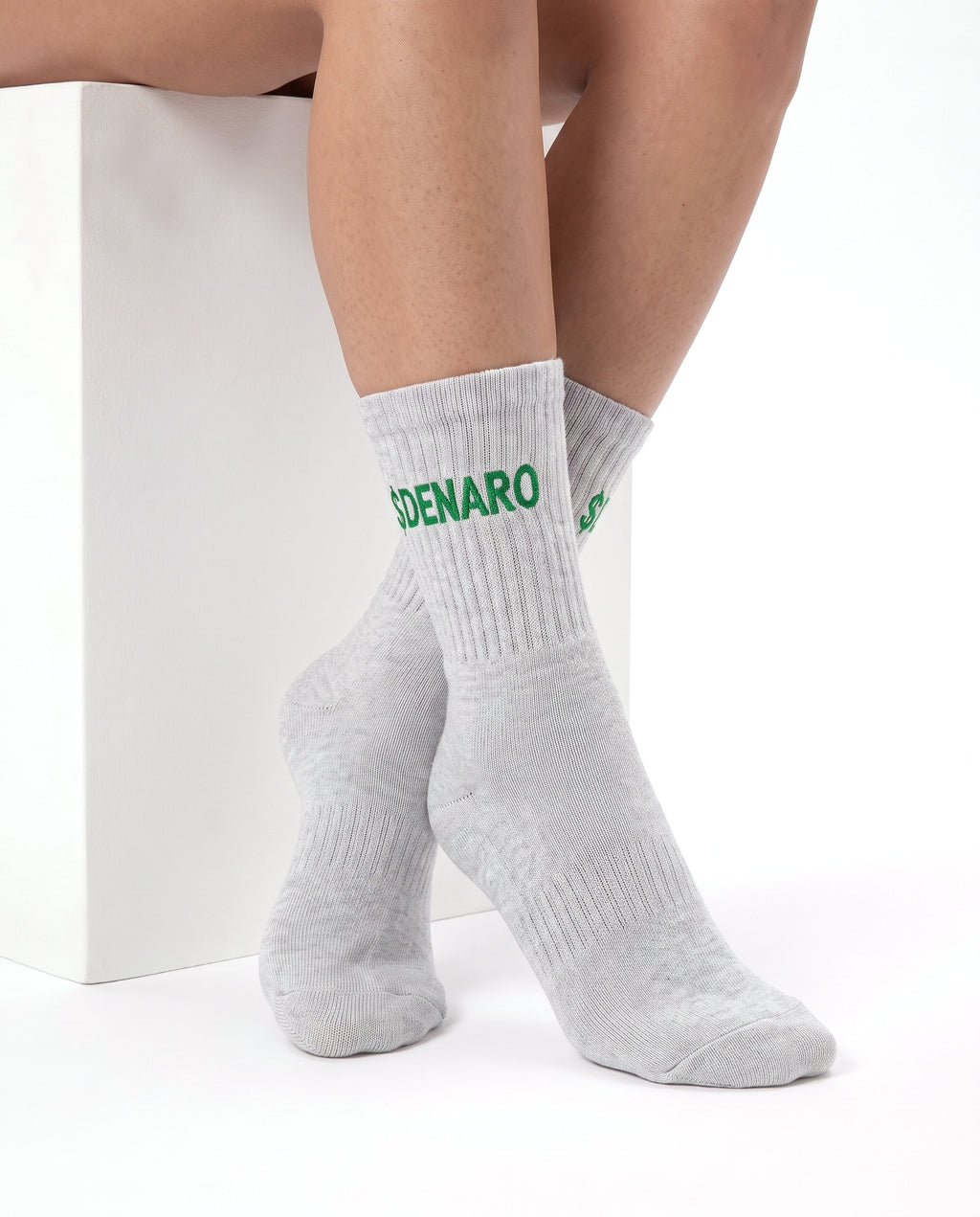 Model wearing Denaro crew socks in heather grey, seated