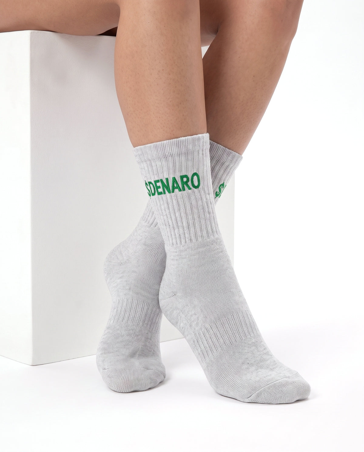 Model wearing Denaro crew socks in heather grey, seated